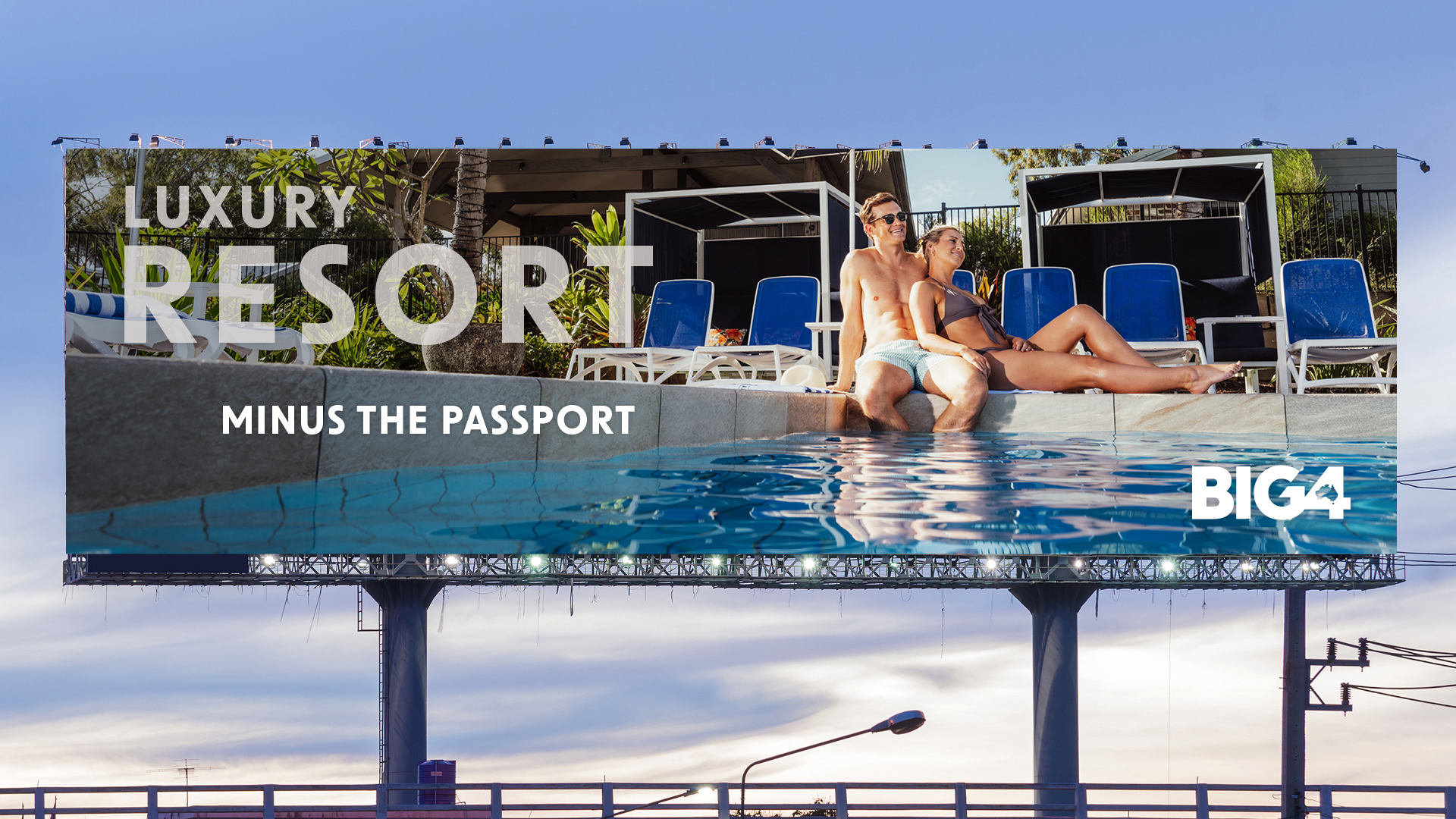 Billboard depicting young couple lounging by the pool, with the tagline 'Luxury Resort Minus the Passport'. Part of Big 4's 'Experience More' campaign by Bellwether Agency, 2022